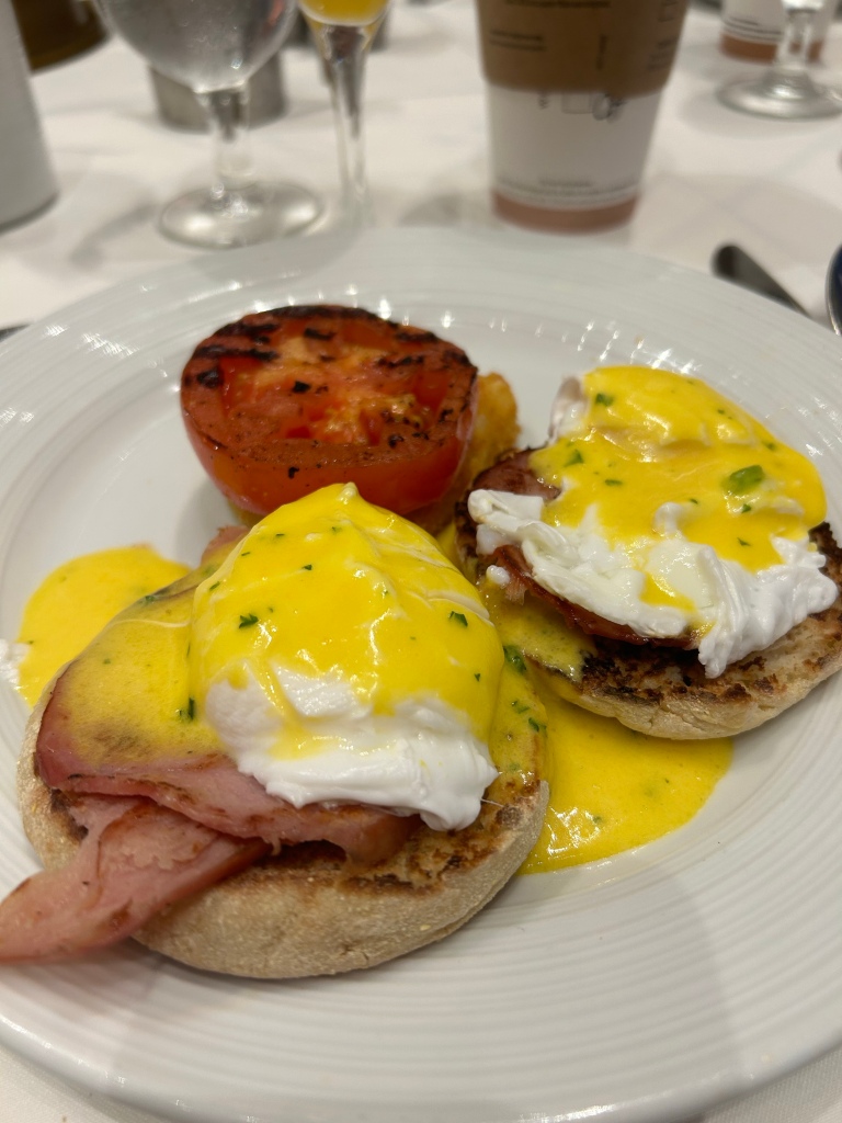 Eggs Benedict on a plate with a roasted tomato